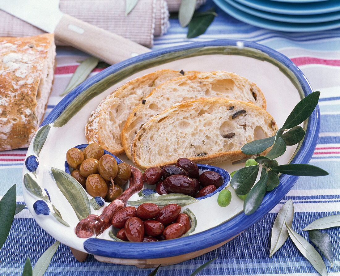 Teller mit Ciabatta und verschiedenen Oliven,  Olivenzweig