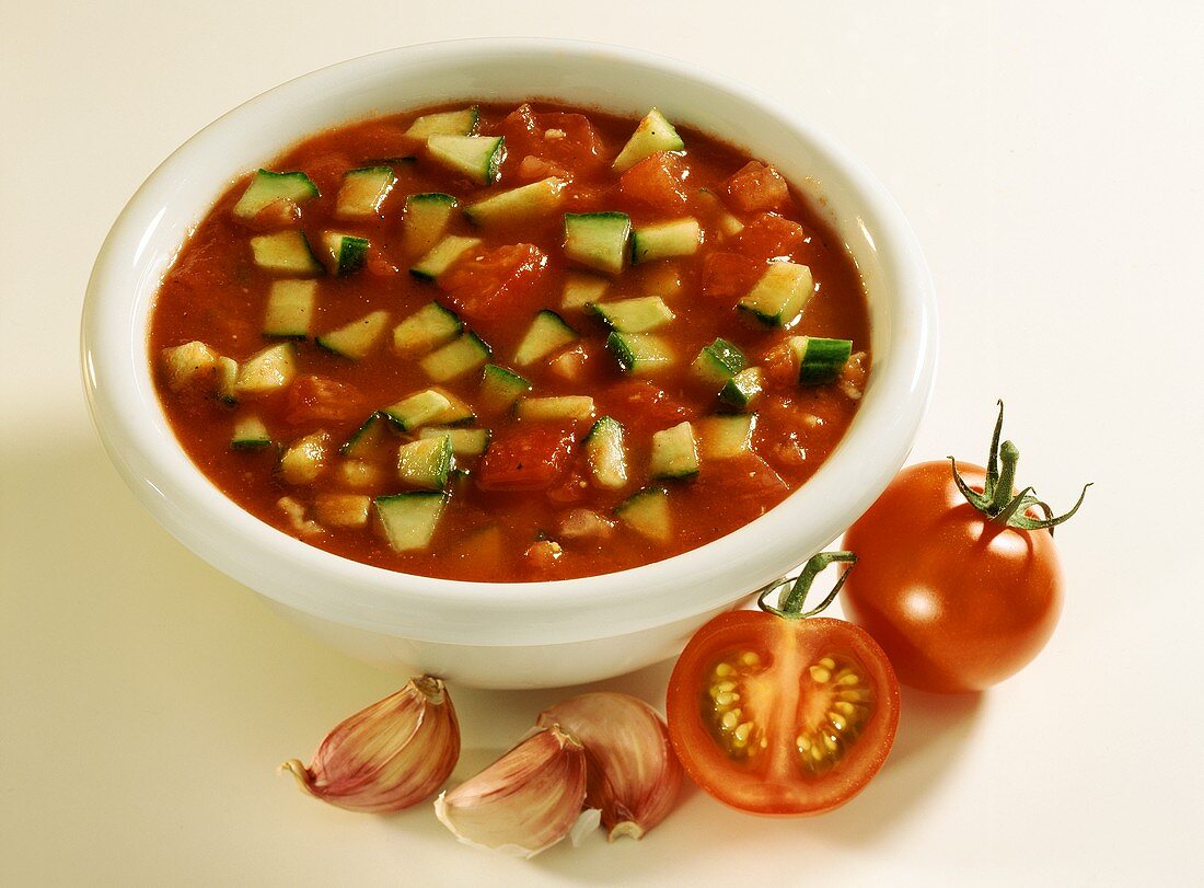 Kalte Tomatensuppe mit Gurkenwürfeln in weißer Schale