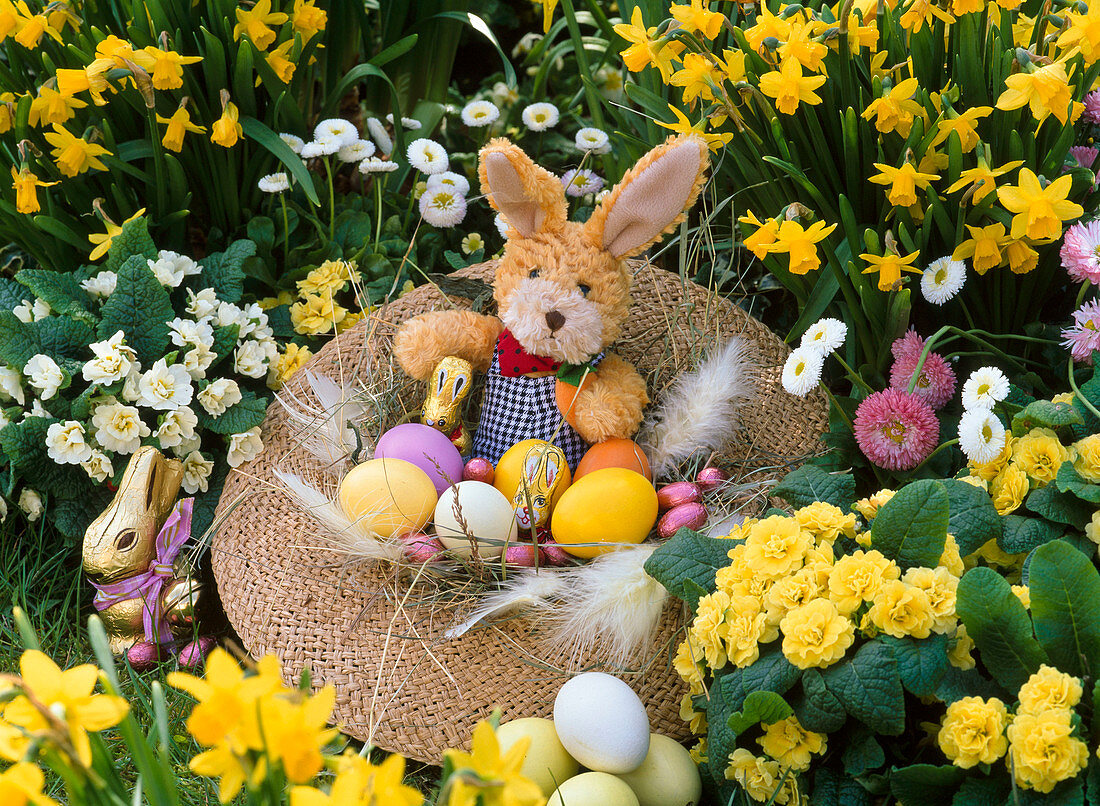 Straw hat as easter nest with easter bunny and eggs in bed