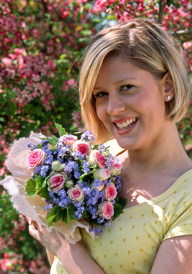 Frau mit Strauß aus Rosa 'Mini Eden'(Rosen), Myosotis (Vergißmeinnicht) und Corylus