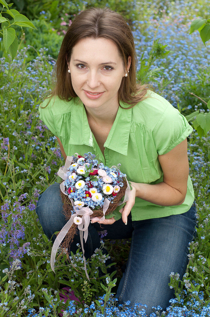 Woman with bouquet of Myosotis (forget-me-nots), Bellis