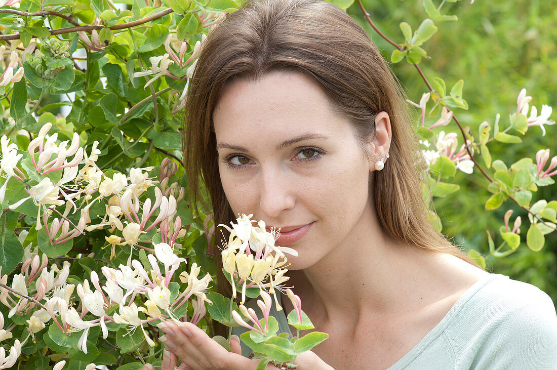 Woman sniffing fragrant Lonicera caprifolium