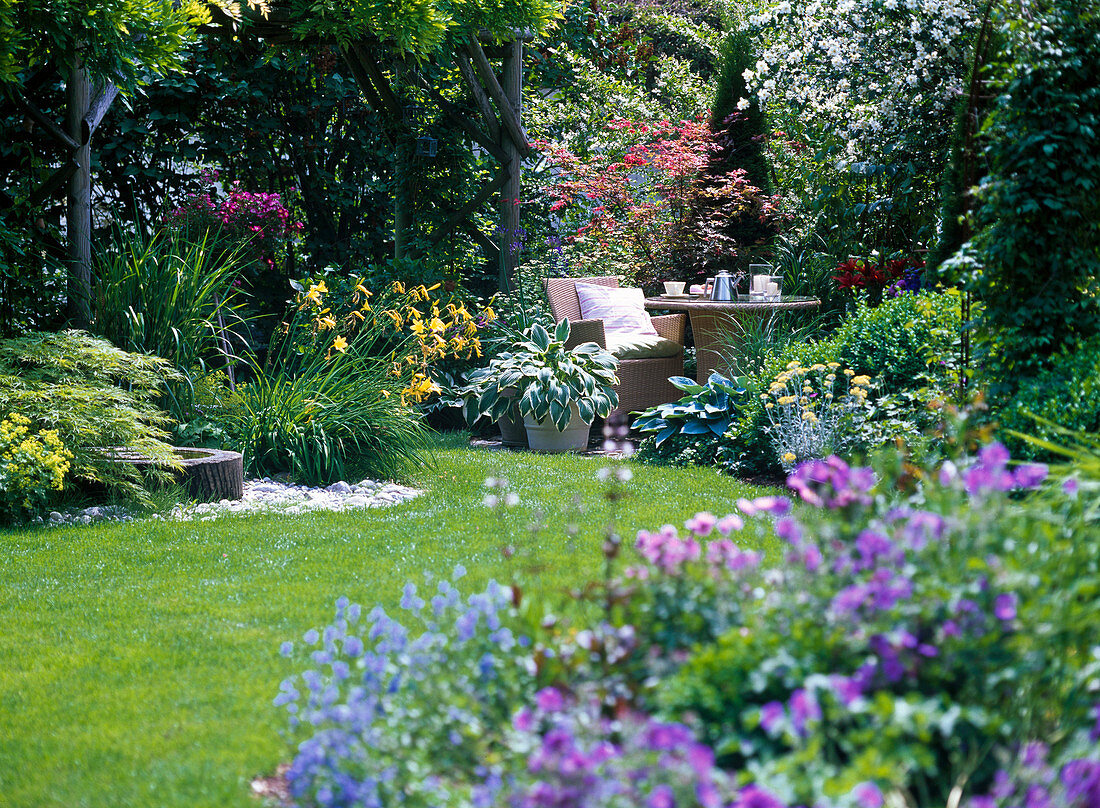 Garden view overlooking small terrace with seating, overgrown pergola