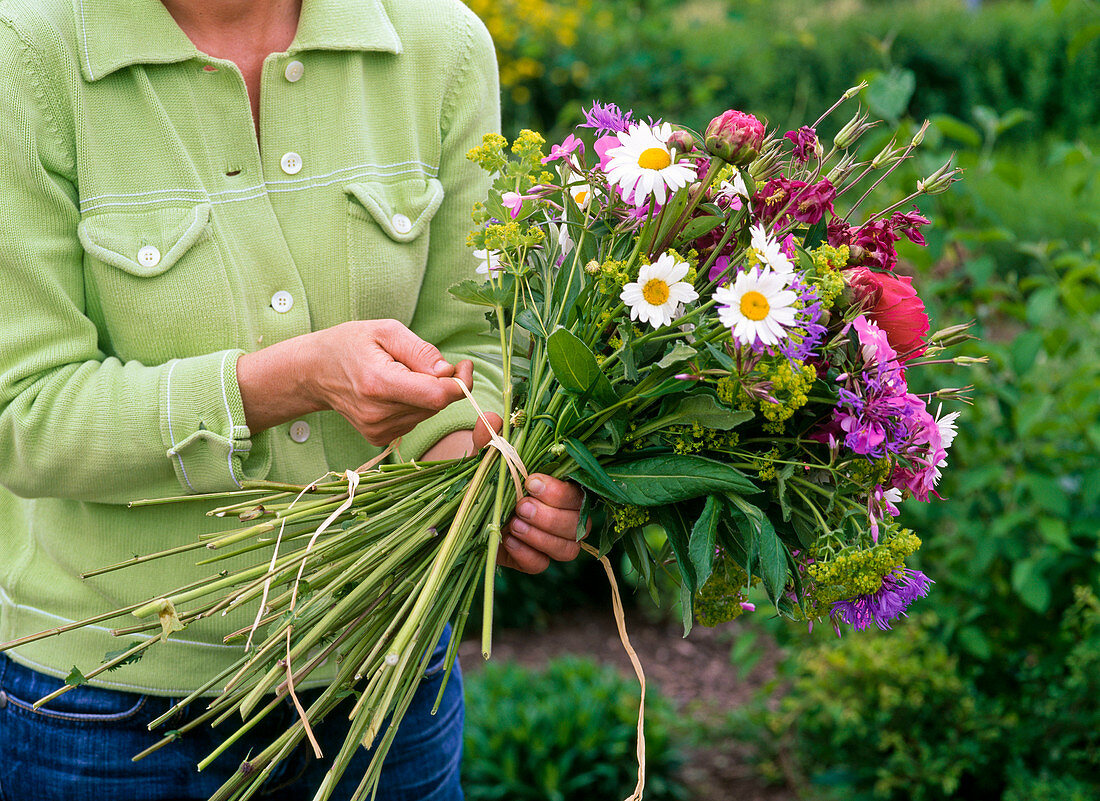 Tying colorful bouquet with peonies