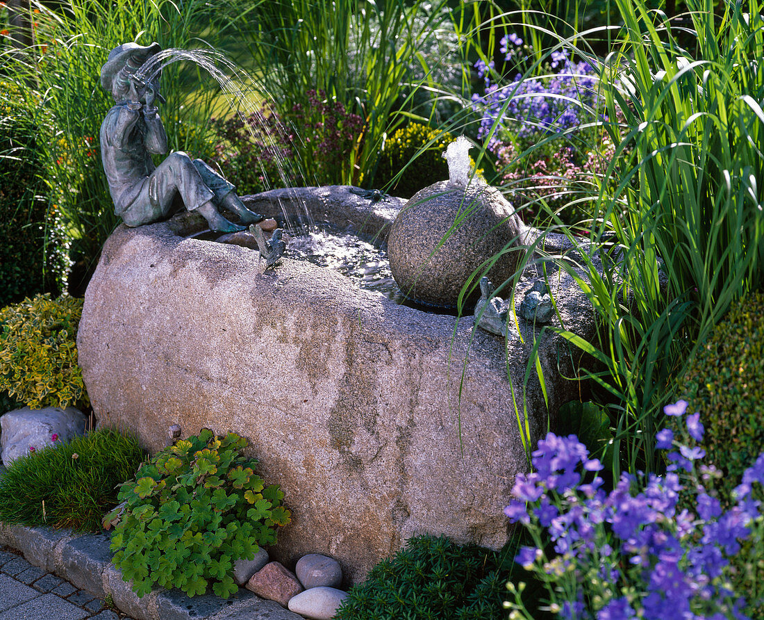 Stone trough with ball and flute player as water feature