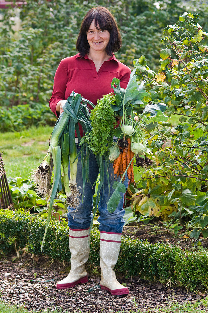 Woman with freshly harvested Daucus carota (carrots)