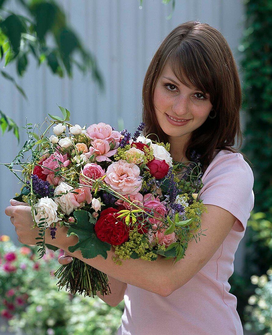 Woman holding bouquet of Rosa (roses), Alchemilla (lady's mantle)