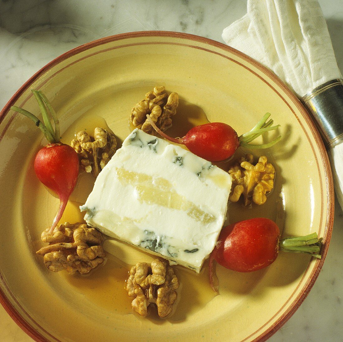 Eine Scheibe Käse-Birnen-Terrine auf Teller mit Walnüssen