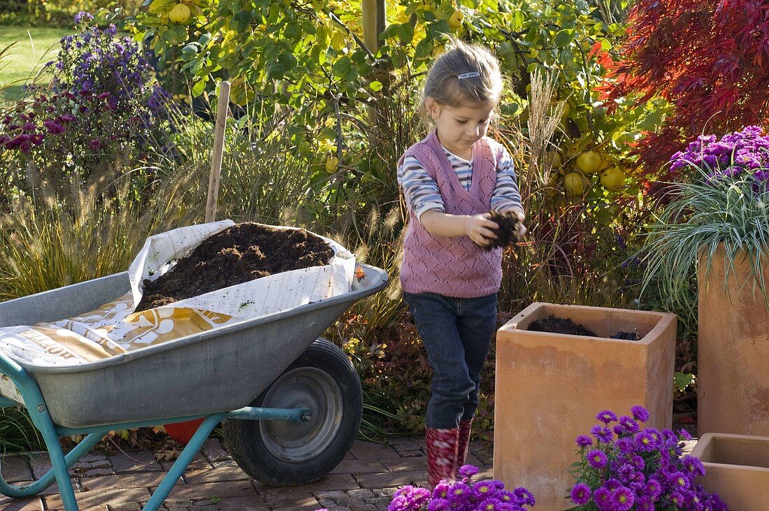 Mother and daughter planting terracotta tubs (2/4)