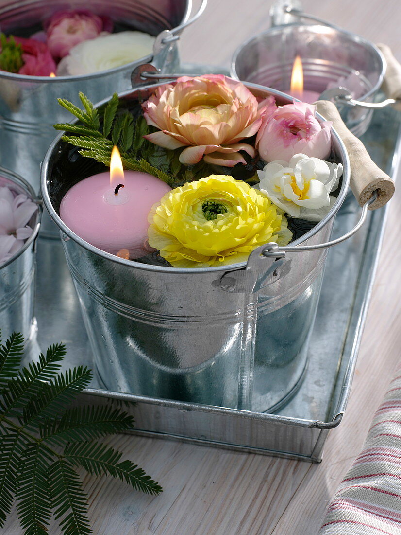 Small buckets with floating candles and flowers