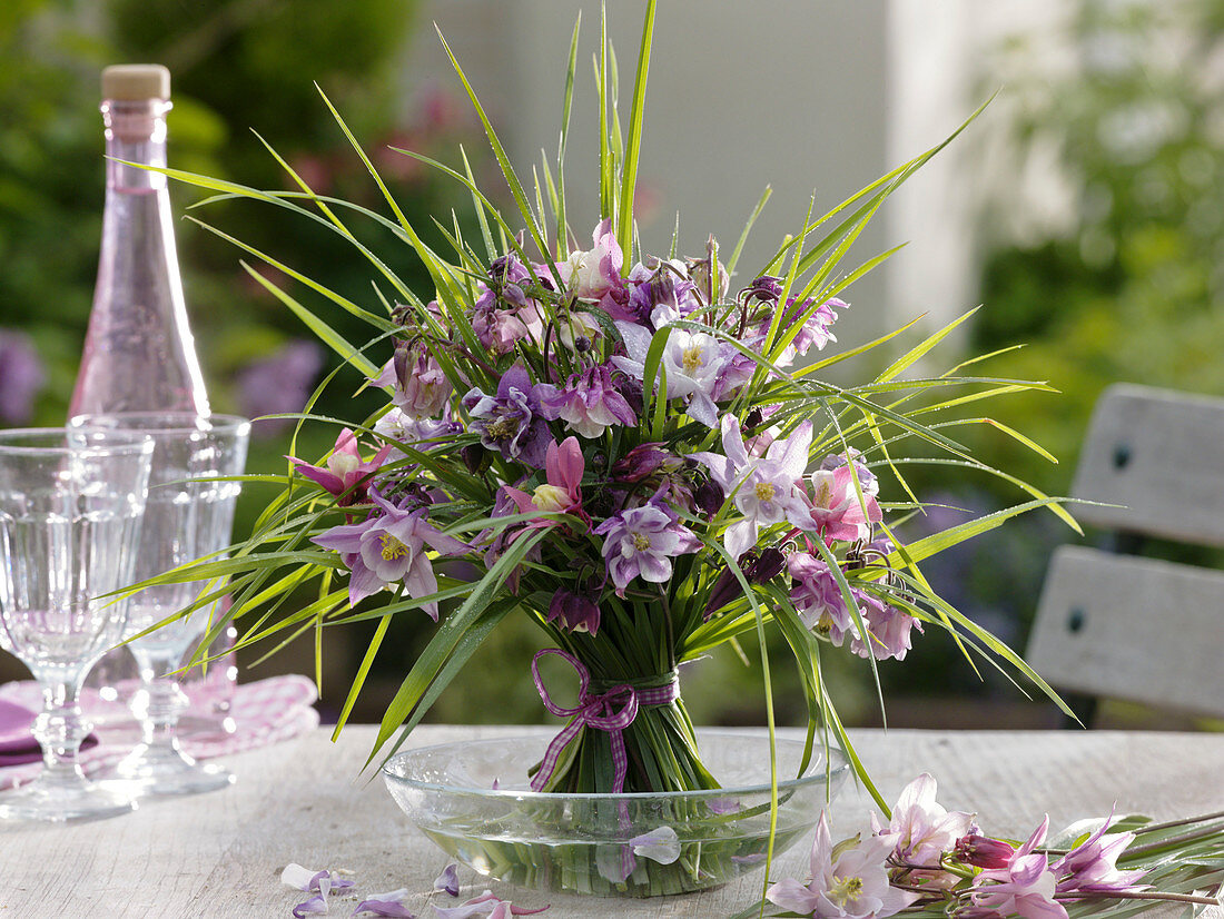 Standing bouquet of Aquilegia (columbine) and grasses in a glass bowl