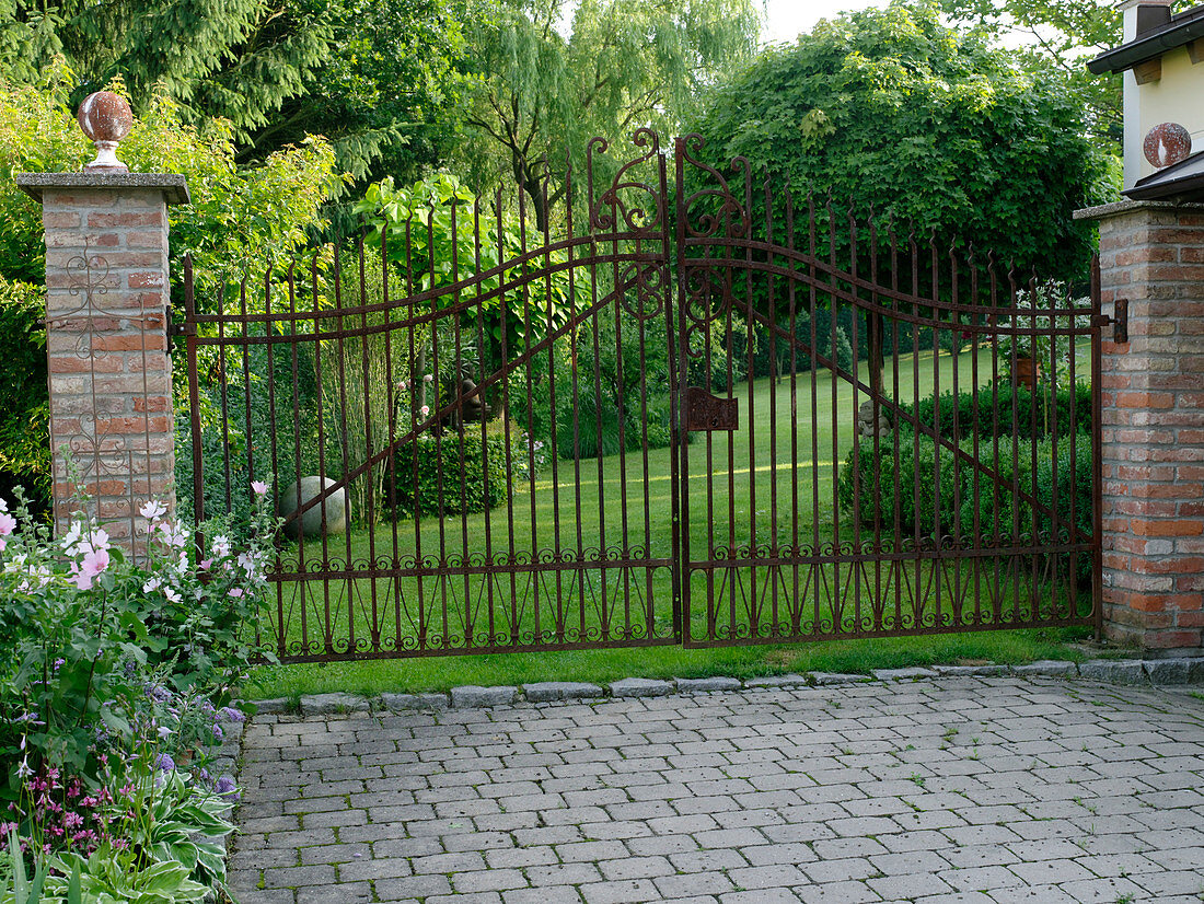 Blick in den Garten durch schmiedeeisernes Tor