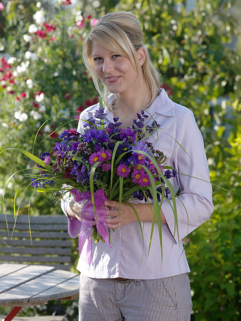 Young woman with bouquet of Callistephus (summer asters), Erigeron