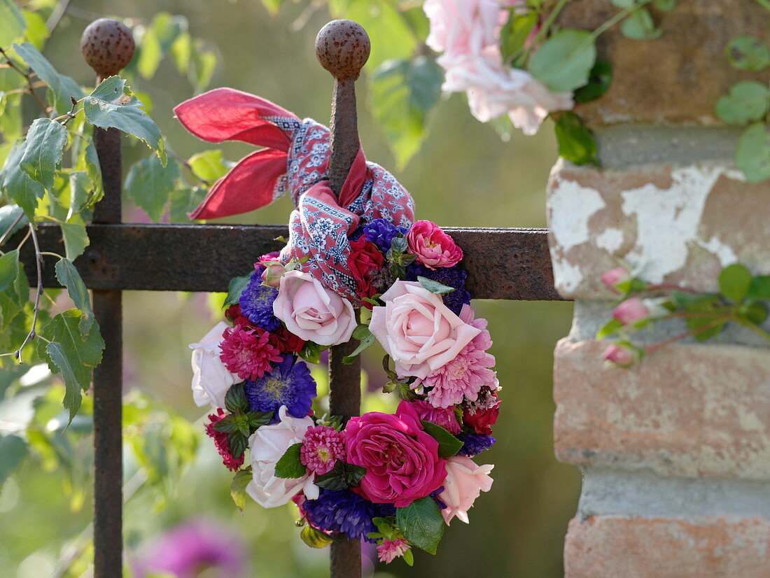 Wreath of roses and summer asters on a fence
