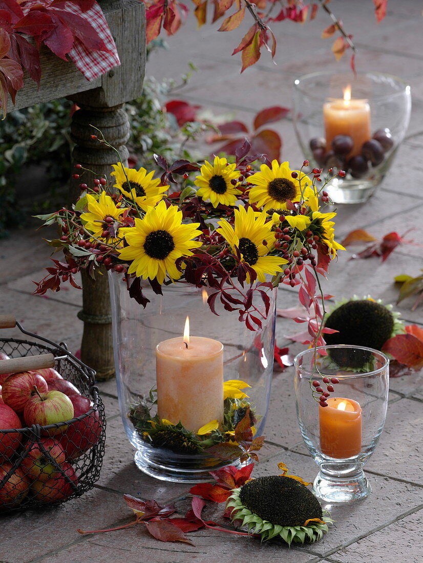 Glaswindlicht mit Kranz aus Sonnenblumen, wildem Wein und Hagebutten