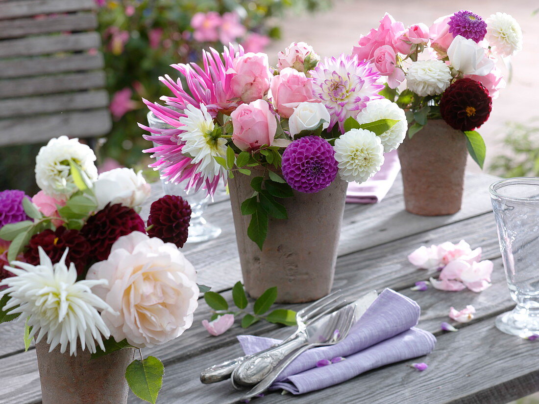 Tischdekoration mit Dahlien und Rosen in Terrakottavasen