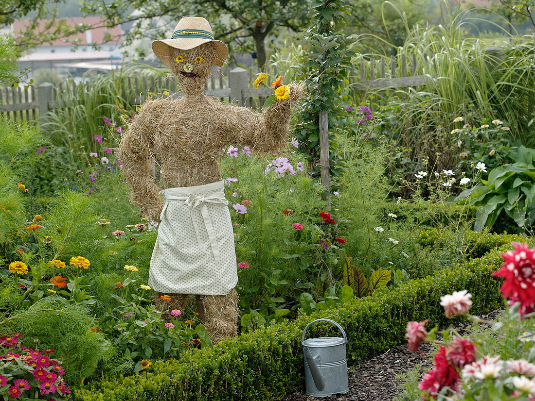 Scarecrow made of straw with straw hat and apron in a country garden