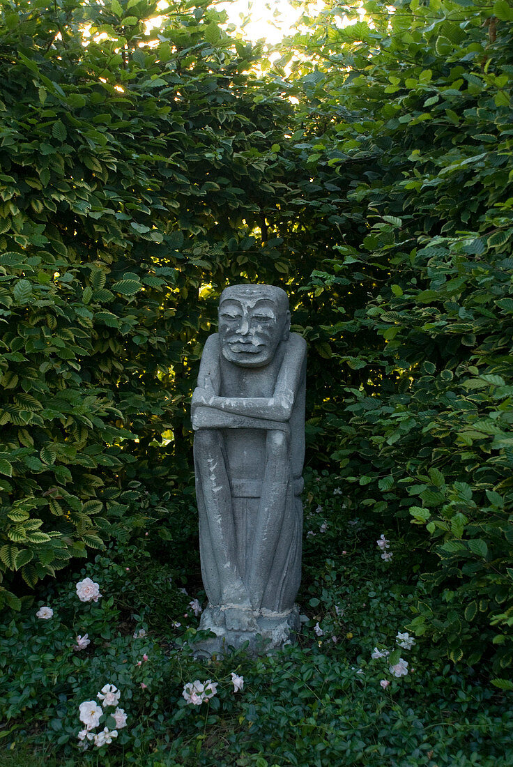 Steinerne Wächter-Figur in einer Nische der Weißbuchen - Hecke (Carpinus)