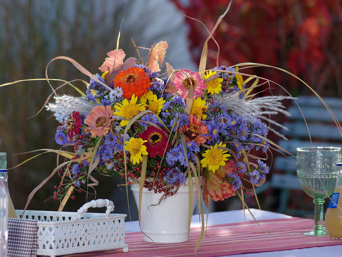 Herbststrauß aus Astern, Zinnien und Gräser auf Tisch