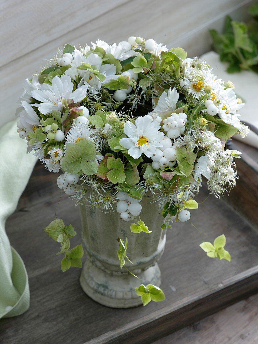 Autumn wreath in green and white lying on vase with foot