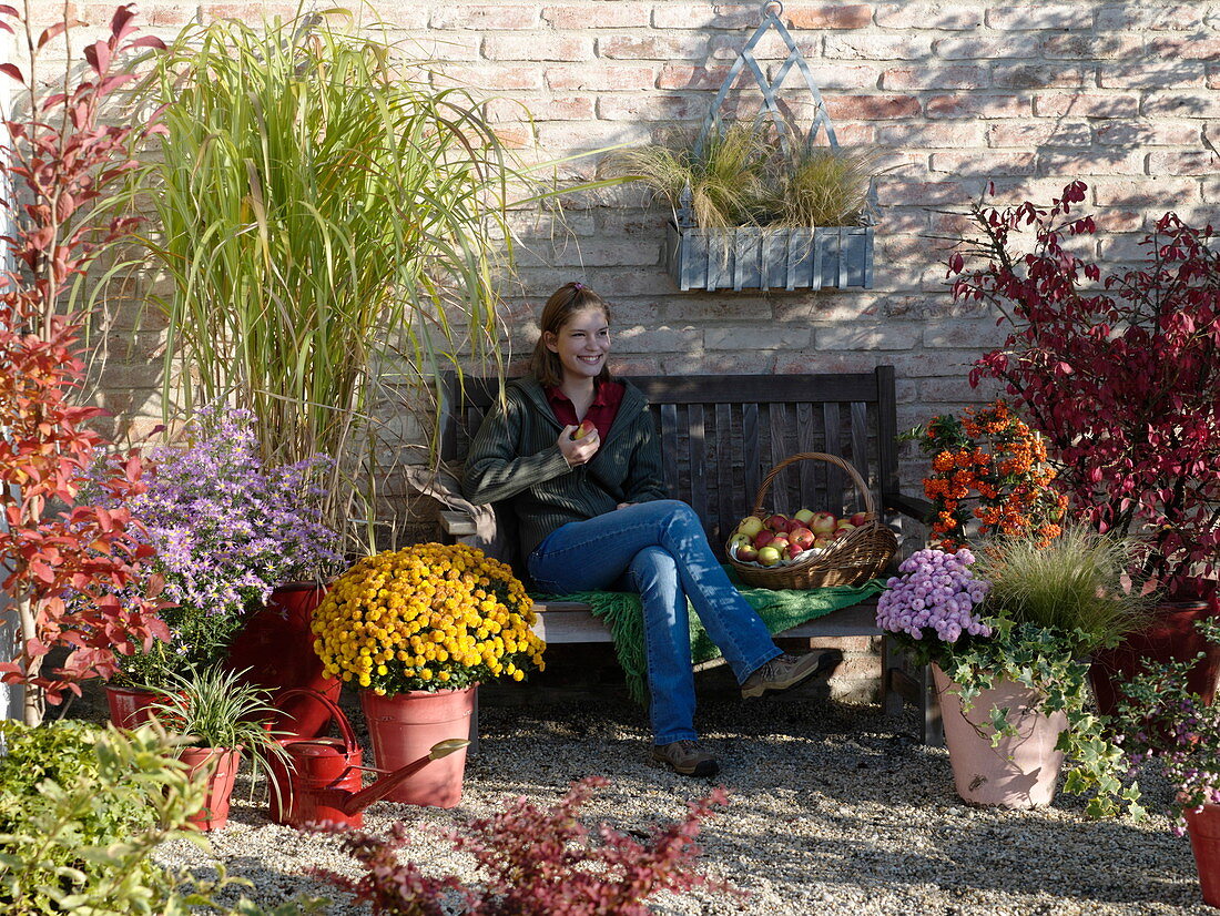 Frau auf herbstlicher Terrasse mit Stauden und Gräsern