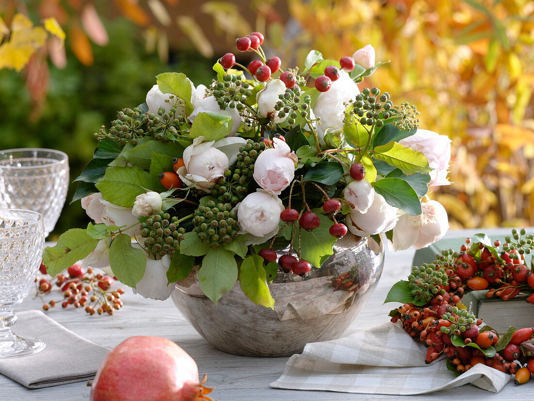 Autumnal bouquet made of roses, ivy and rosehips in a silver vase