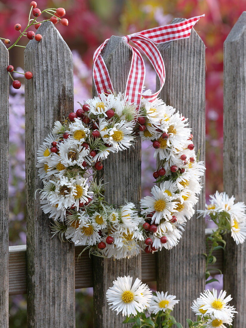 Small blackberries and rosehips autumn wreath on a wooden fence