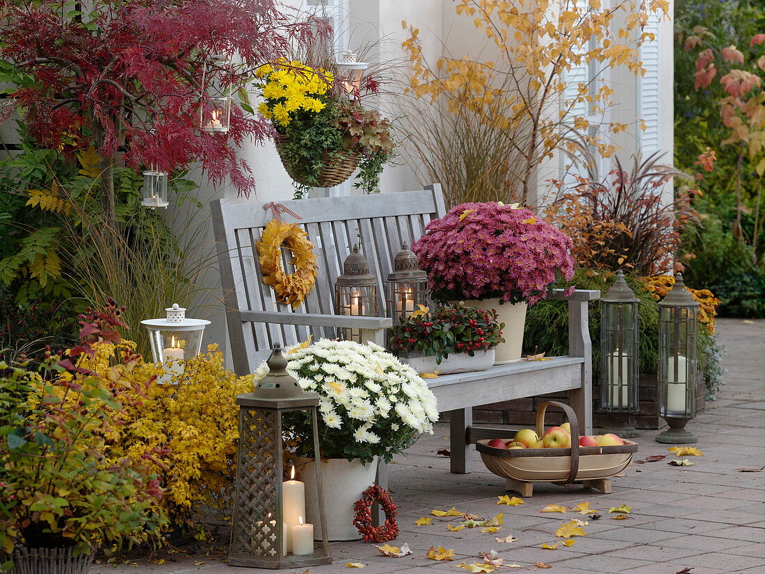 Herbstliche Terrasse mit Holzbank und Laternen