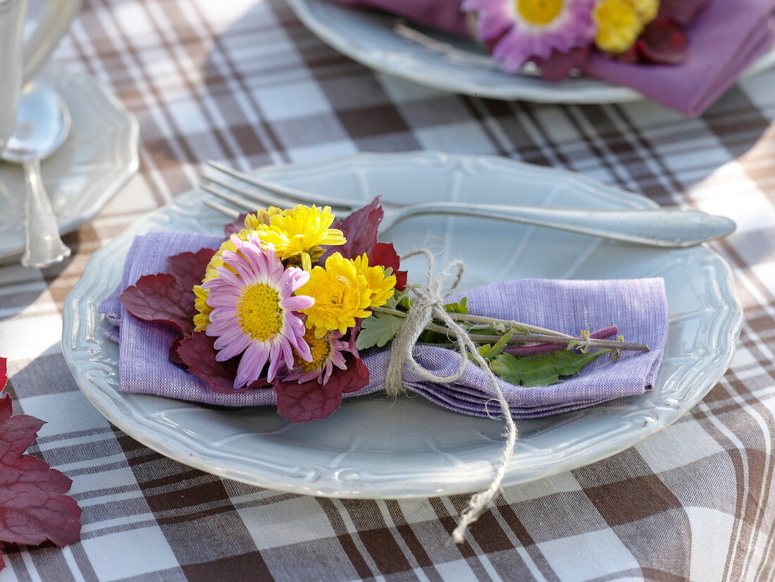 Herbstliche Tischdeko mit Herbstchrysanthemen und Heuchera-Blättern