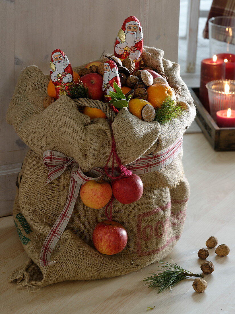 Basket with apples (Malus) and oranges (Citrus sinensis) in jute bag
