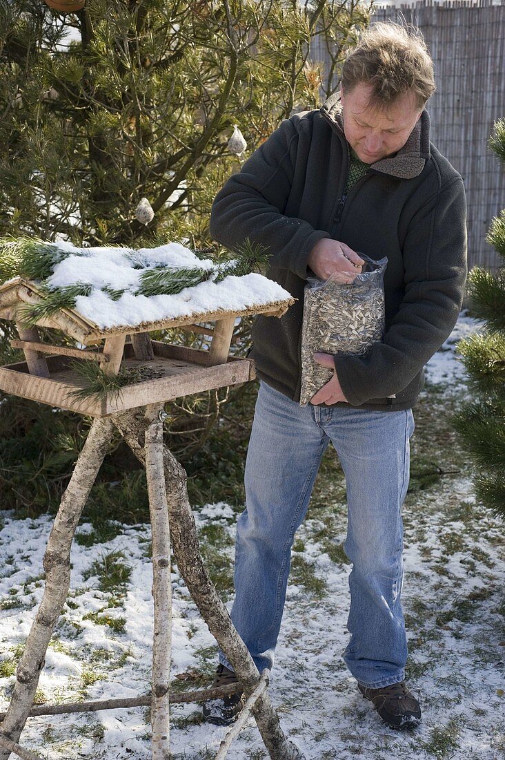 Mann füllt Vogelfutter in Vogelhaus