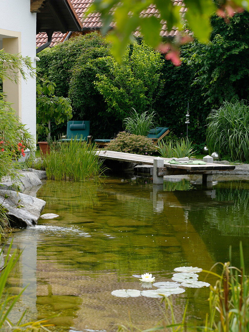 Schwimmteich mit Holzsteg eingefaßt mit Granit-Blöcken