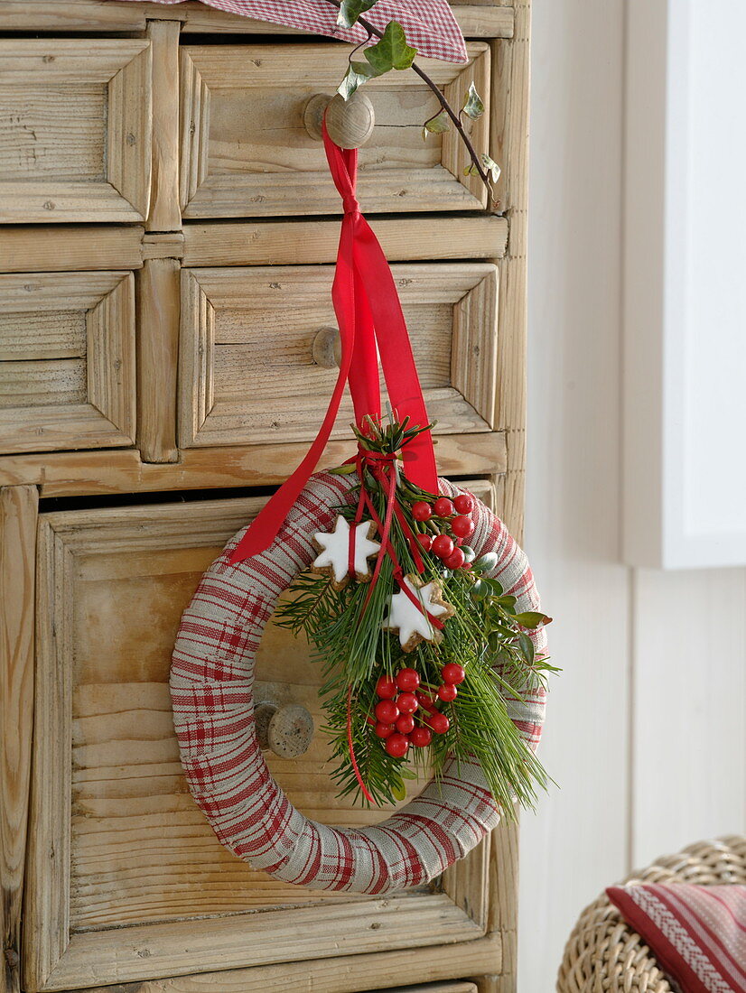 Christmas wreath made of straw ring wrapped with red and white chequered ribbon