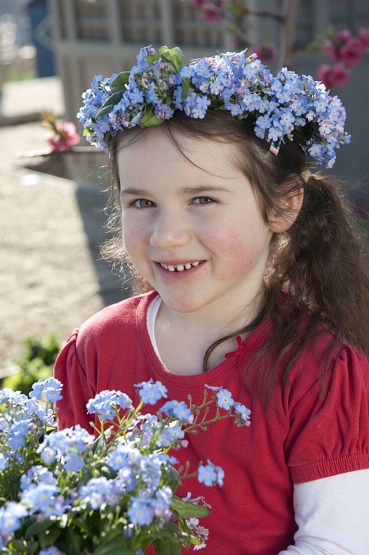 Mädchen mit Myosotis (Vergißmeinnicht) im Topf und als Kranz