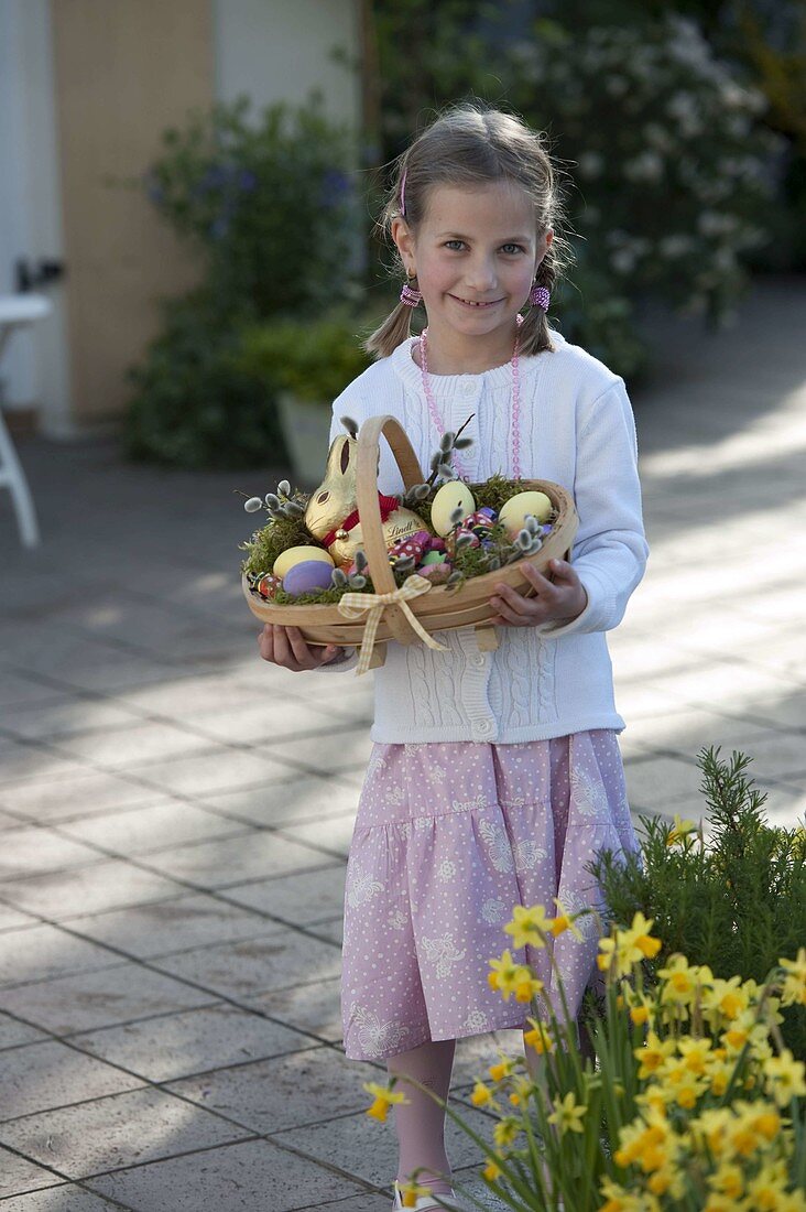 Girl with Easter basket: chocolate Easter bunny, Easter eggs, lucky beetle