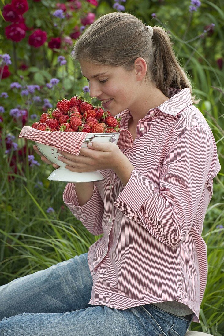 Young woman enjoying the smell of freshly picked strawberries