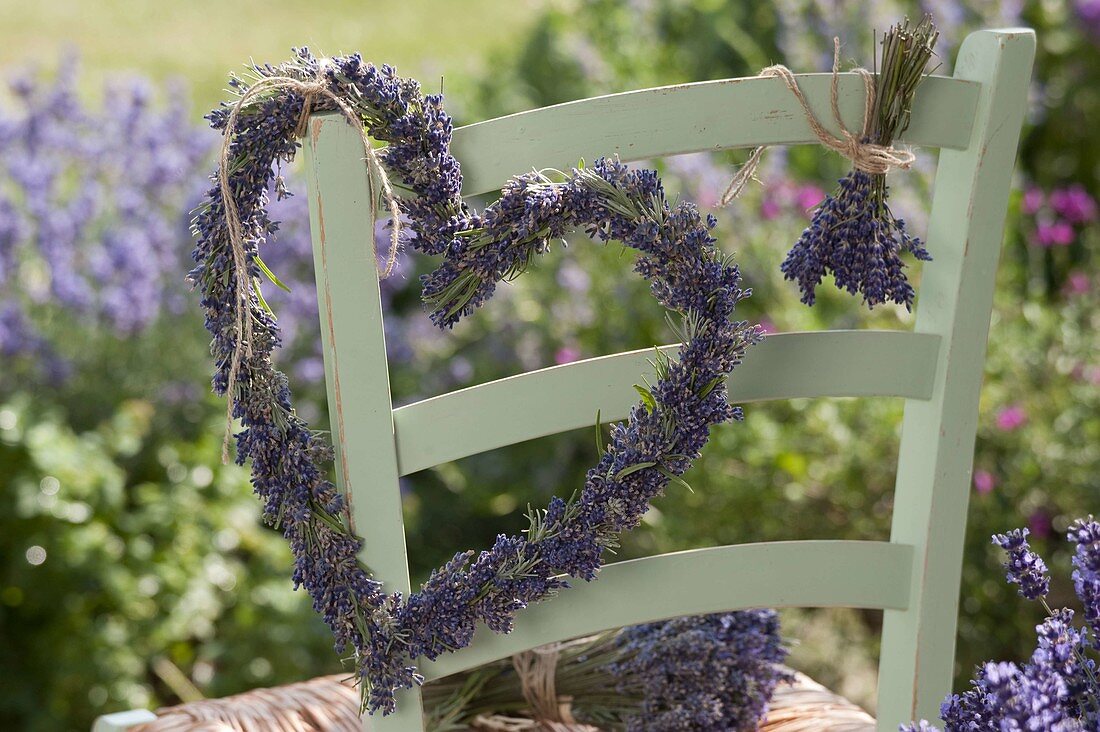 Herz und Strauß aus Lavendel (Lavandula) an Stuhllehne gehängt