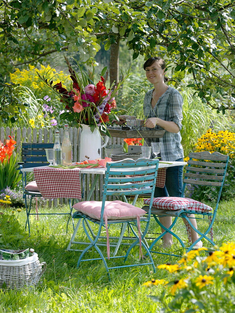 Table with gladiolus-dahlia bouquet under apple tree