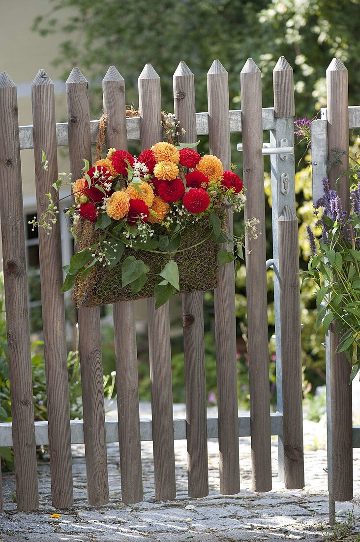 Homemade moss bag with dahlias as a welcome at the garden gate