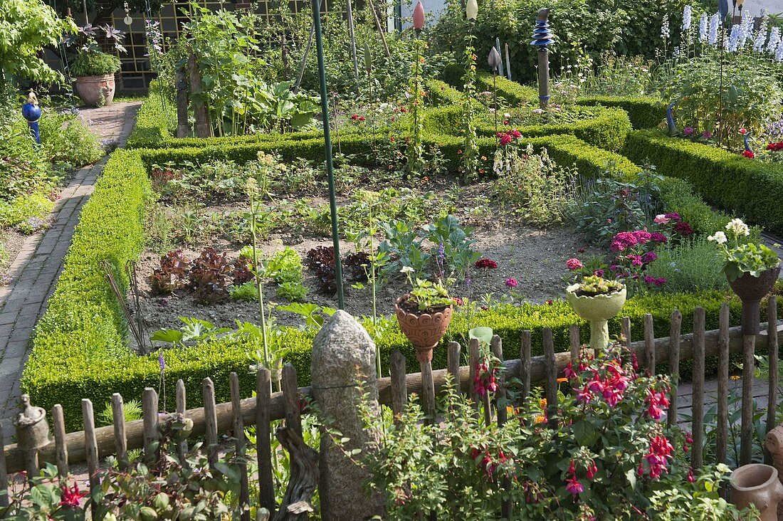 Artist's garden: Garden fence with fuchsias and pottery art objects