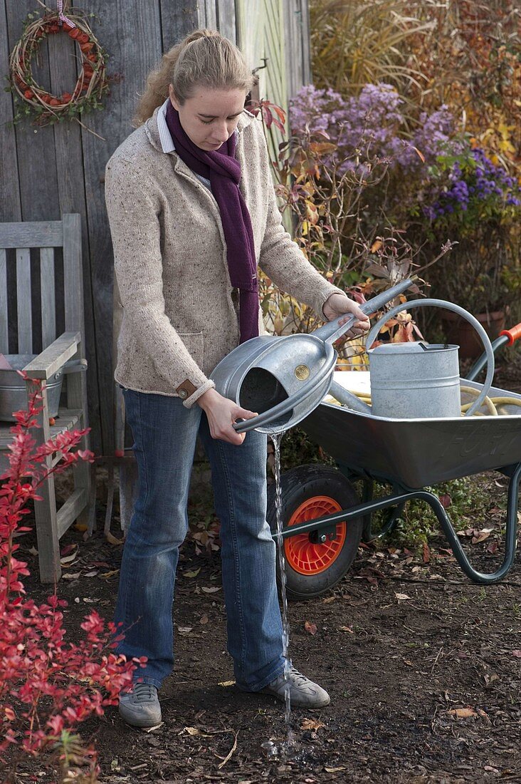 Woman emptying watering can for winter storage