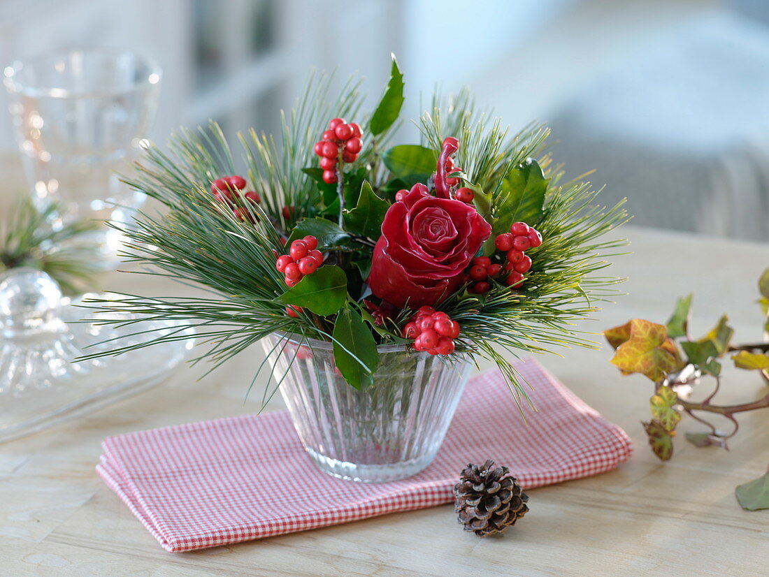 Small winter arrangement with waxed rose (Rosa), holly (Ilex)