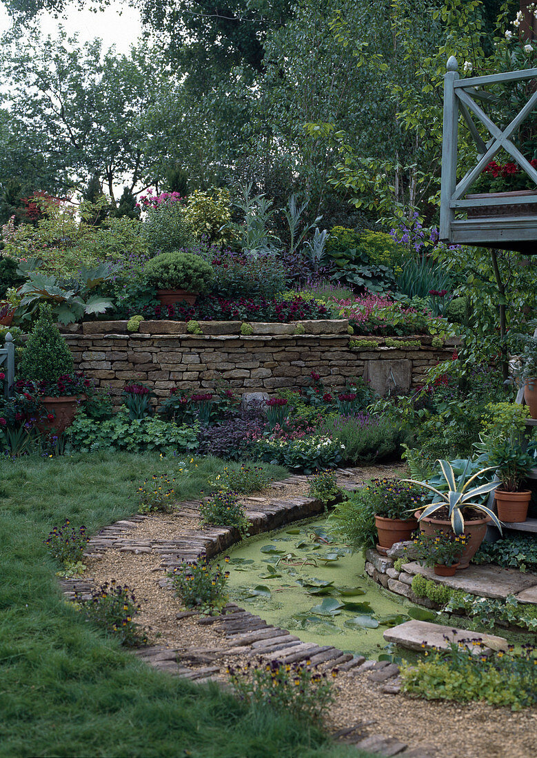 Slope garden with dry stone wall, stream next to gravel path