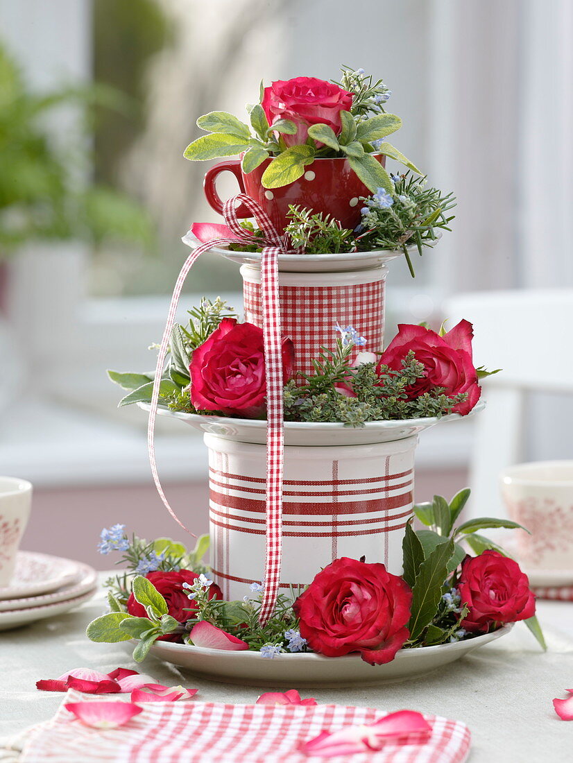 Homemade cake stand made of plates, cups and cans with roses and herbs