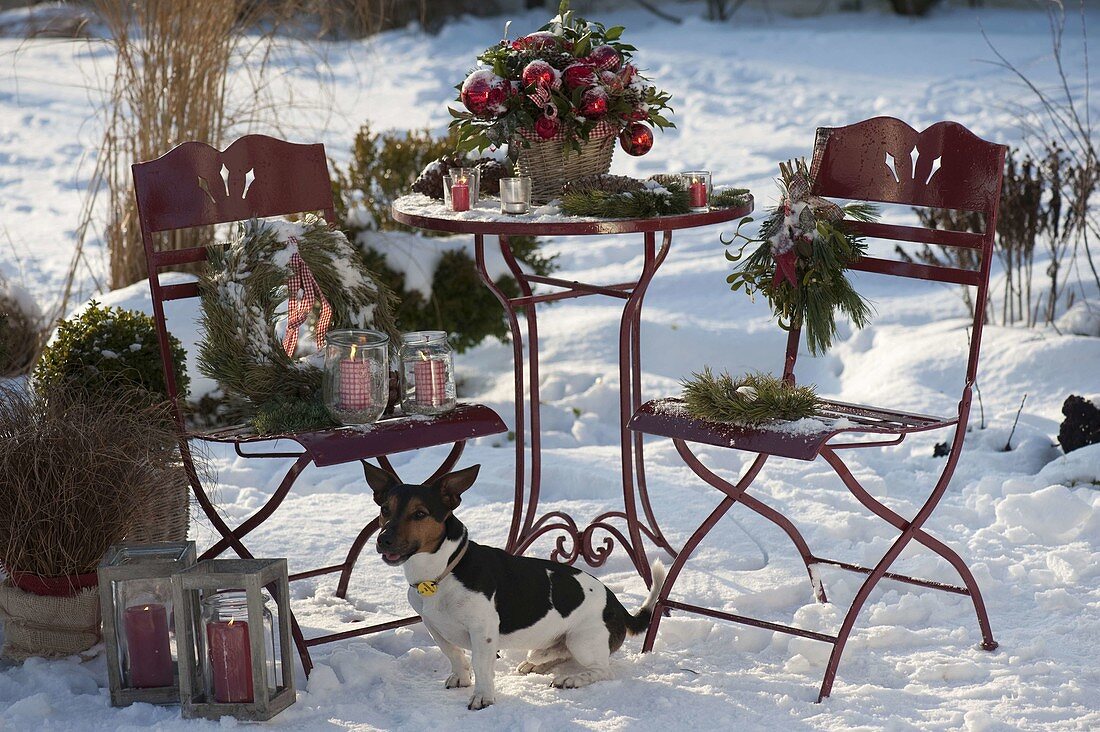 Verschneite Terrasse weihnachtlich geschmückt mit Strauß aus Ilex