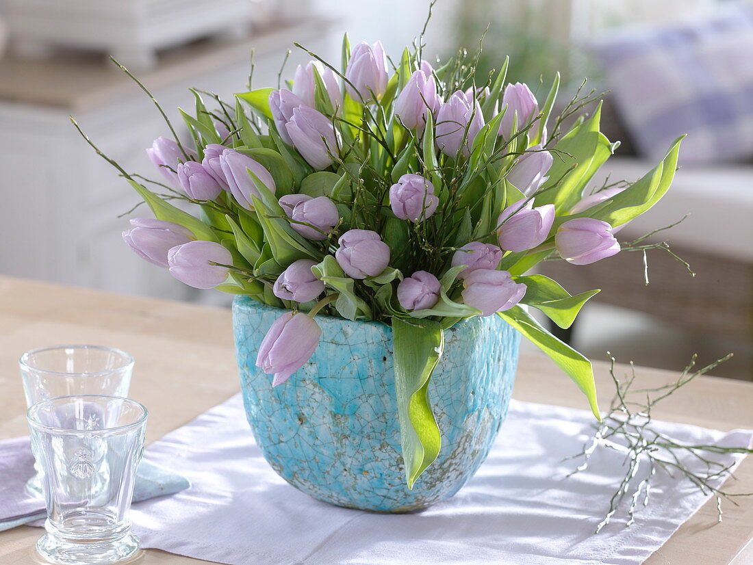 Tulipa (tulips) and branches of Vaccinium (blueberry) in a turquoise vase