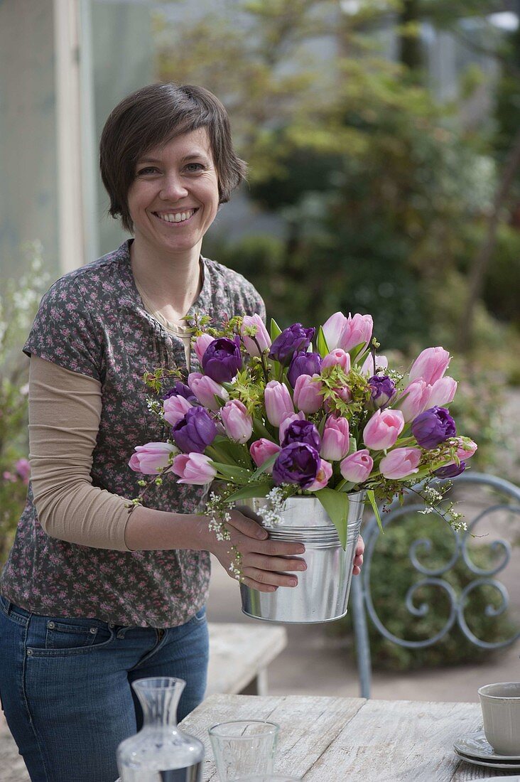 Frau mit Frühlingsstrauß aus Tulpen und Gehölz-Zweigen