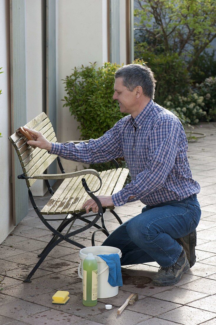 Frühjahrsputz: Mann reinigt Gartenbank
