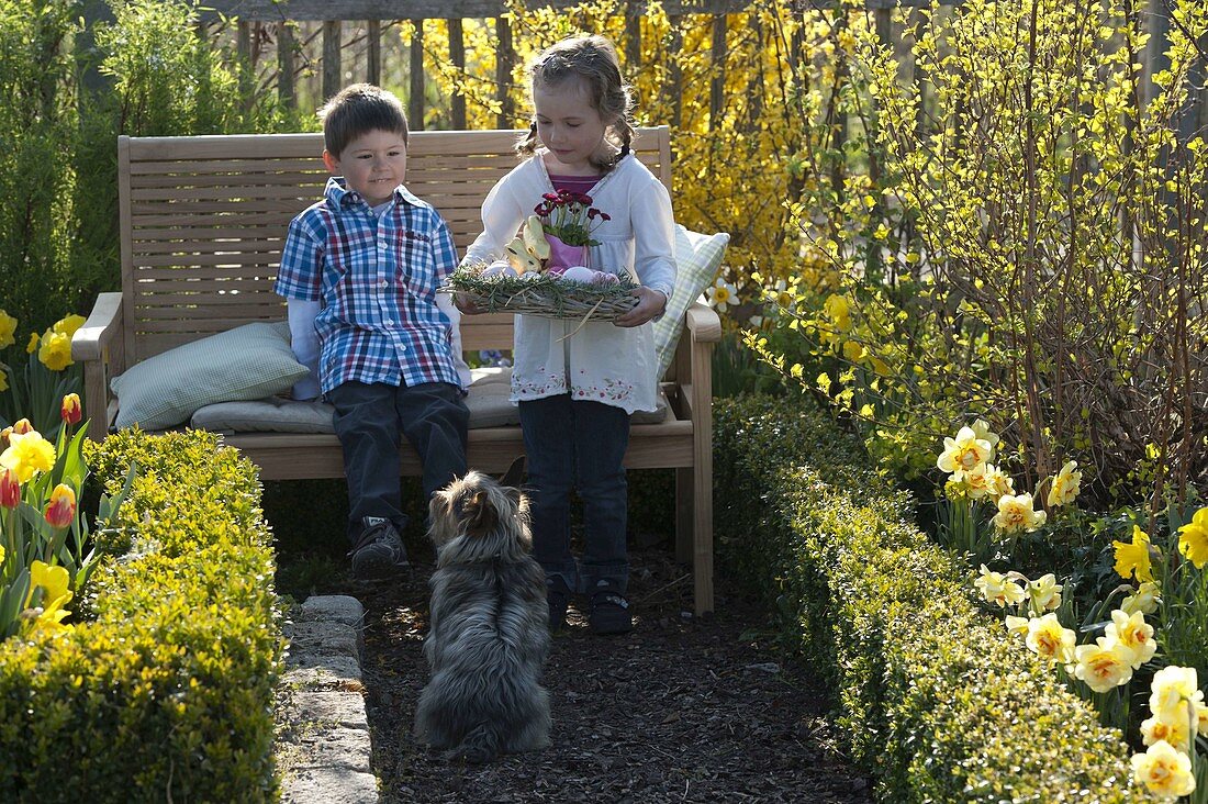 Kinder mit Osternest im Bauerngarten