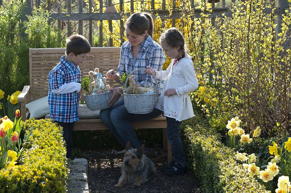 Frau und Kinder mit Osternestern im Bauerngarten